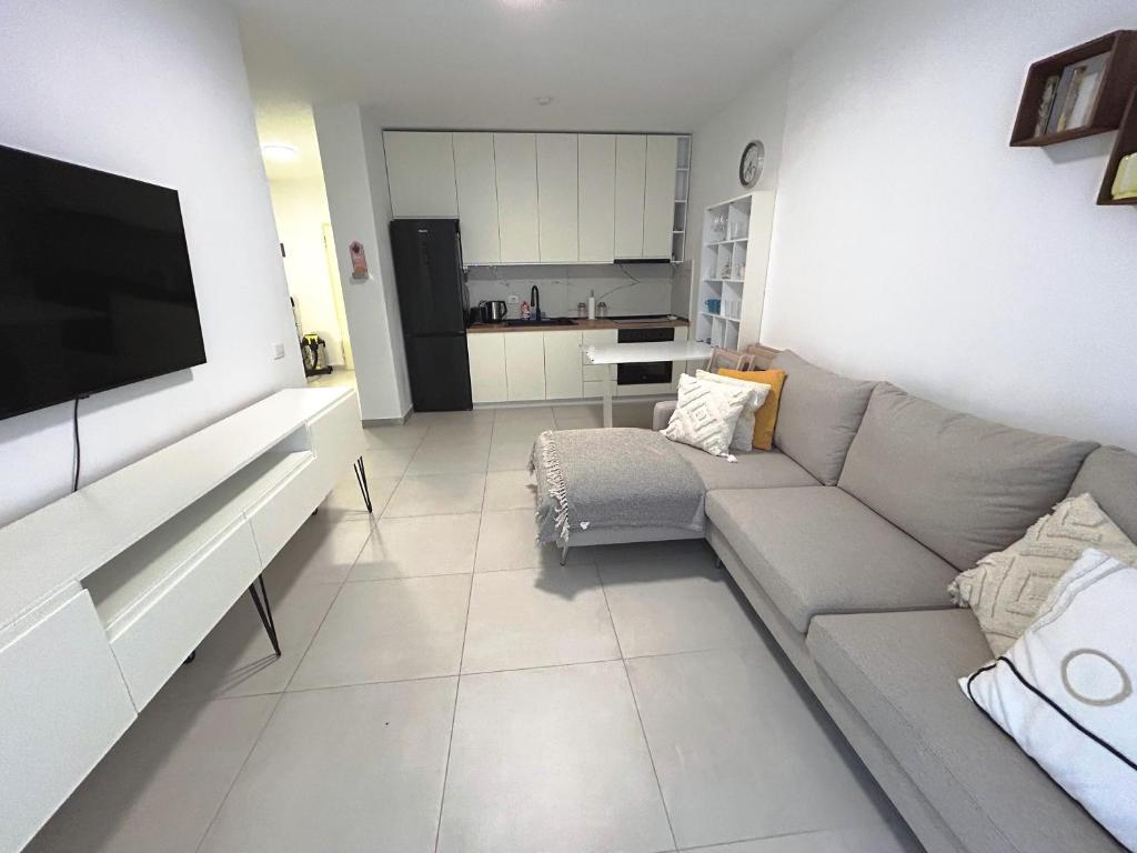 a living room with a couch and a television at Sunshine Apt Qerret-Golem Beach-Self-Check-in in Golem