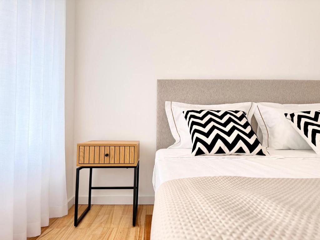 a bed with black and white pillows and a side table at Mouzinho Living Centro & Mar in Póvoa de Varzim