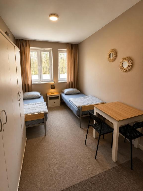 a room with two beds and a table and chairs at Dom Winnica noclegi in Sochaczew