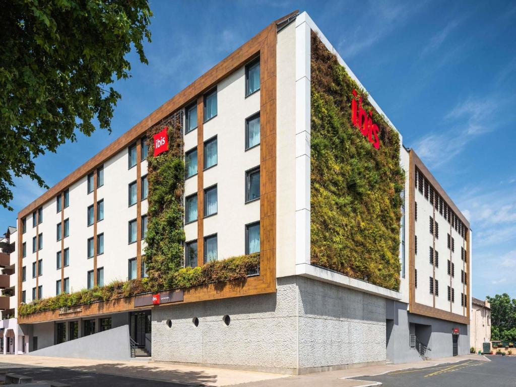a building with a green wall on the side of it at ibis Lyon Sud Oullins in Oullins