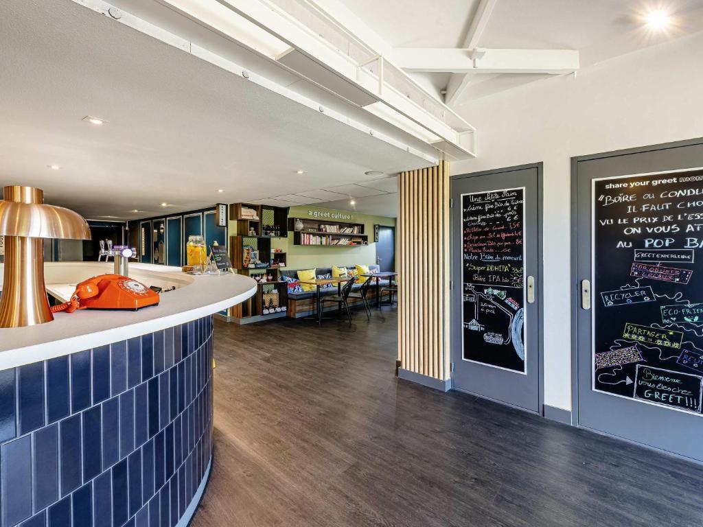 a restaurant with a bar with a chalkboard on the wall at Greet Hotel Bordeaux Floirac Arena in Floirac