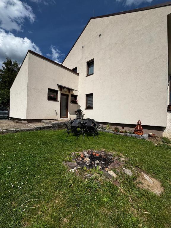 a white building with a grassy yard in front of it at Apartmán Kocourkov in Jáchymov