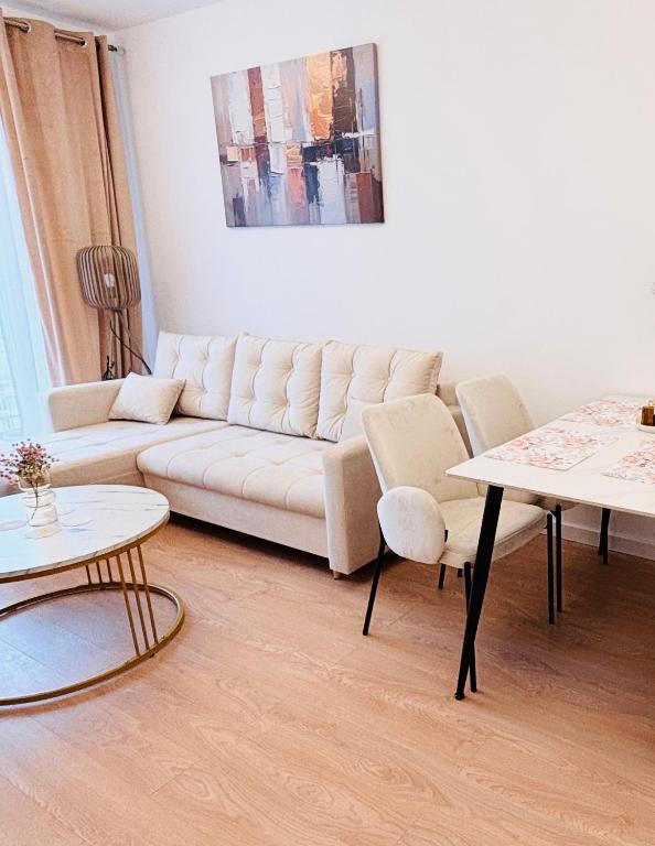 a living room with a white couch and two tables at Lotus Apartments Impero separate kitchen two rooms parking balcony in Ostrołęka