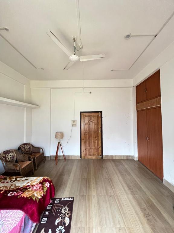 an empty living room with a couch and a ceiling fan at Kopou Homestay in Jorhat