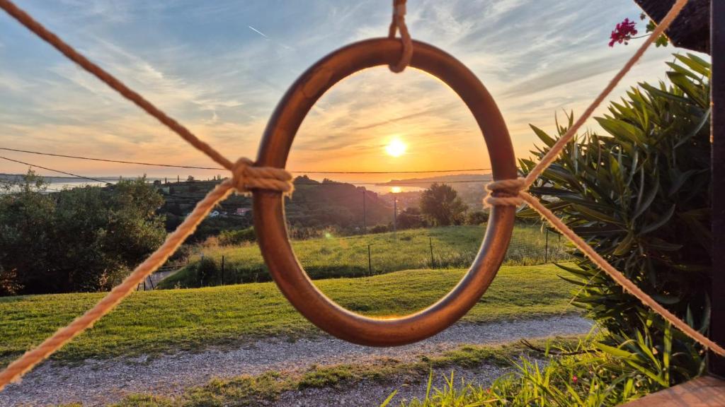 a sunset seen through a wooden ring in a swing at Apartment Sunset View in Portorož