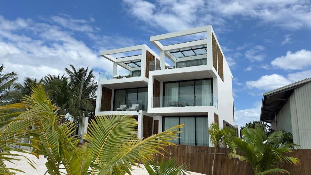 a white building with palm trees in front of it at LuxVilla Modern Beachfront in the Village in Caye Caulker