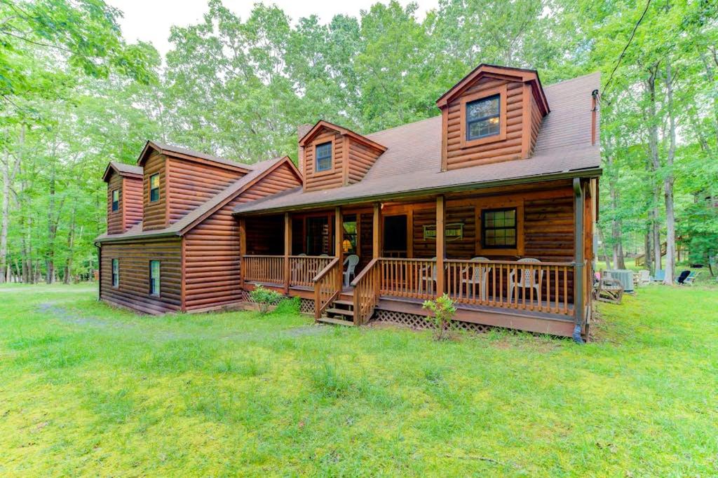a log cabin with a large porch on a field at Lazy Bear Lodge in Swanton