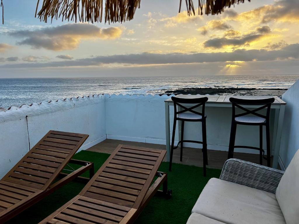 two chairs and two stools on a balcony overlooking the ocean at El Cotillo Mar Beach in El Cotillo