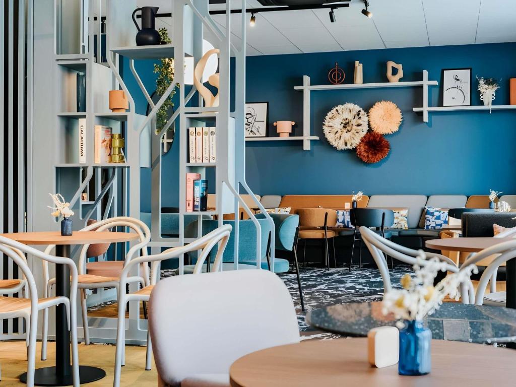 a restaurant with blue walls and tables and chairs at Mercure Brest Centre Port in Brest