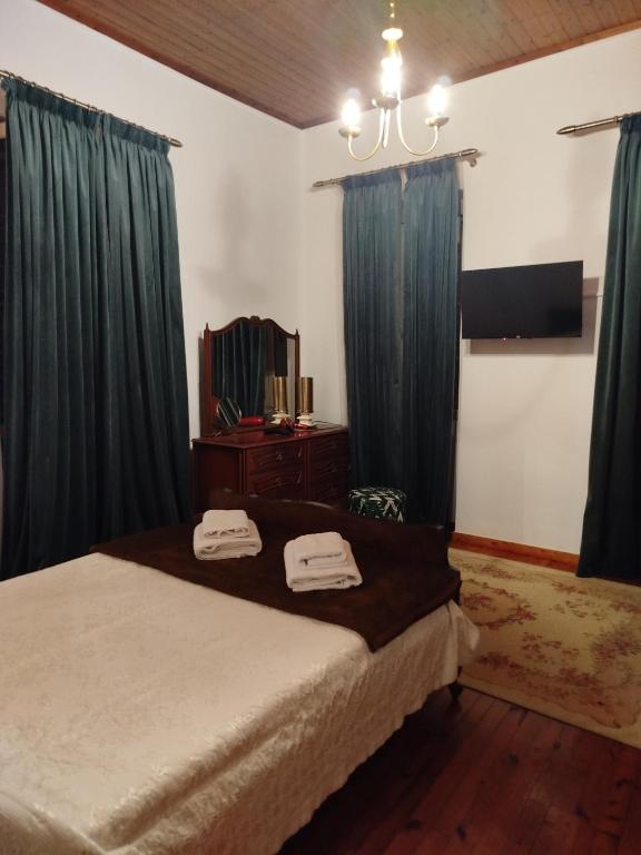 a bedroom with a bed with blue curtains and a mirror at Αιθεροβάμων - Etherovamon in Areopoli