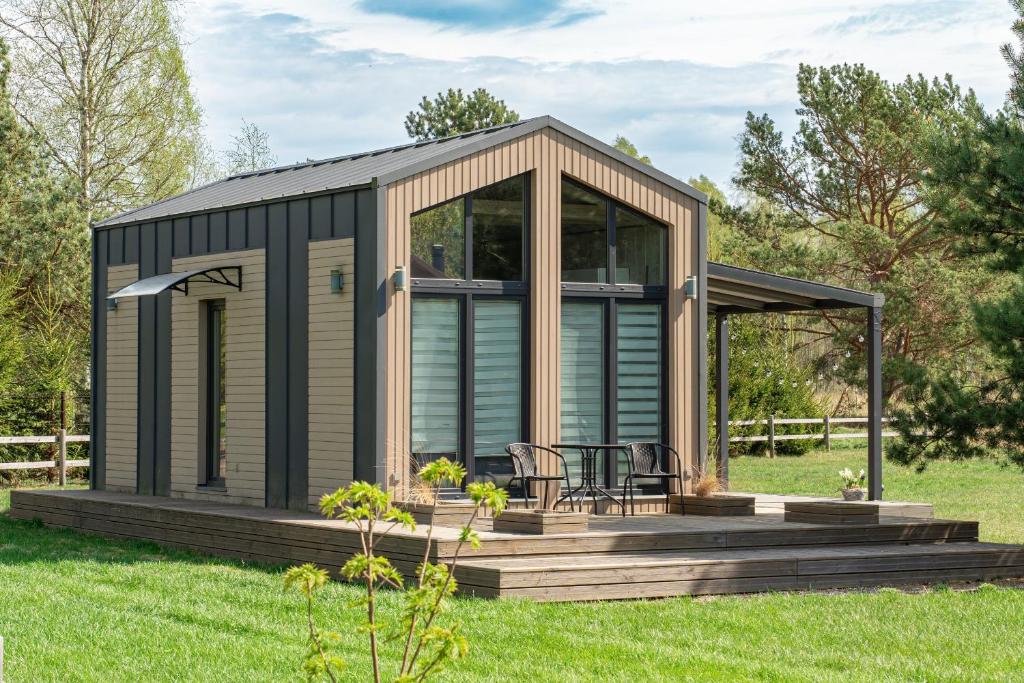 a modular house with a deck in a field at Forrest Guest House Ameli in Ķesterciems