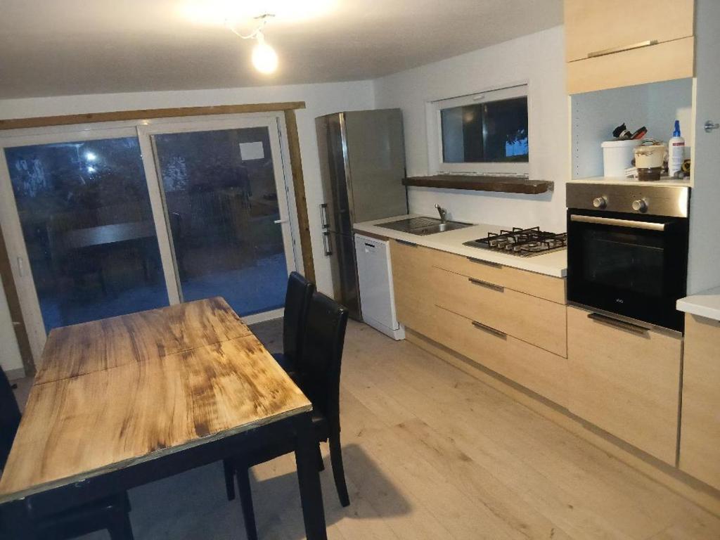 a kitchen with a wooden table and a kitchen with a stove at Chez vous in Dirinon