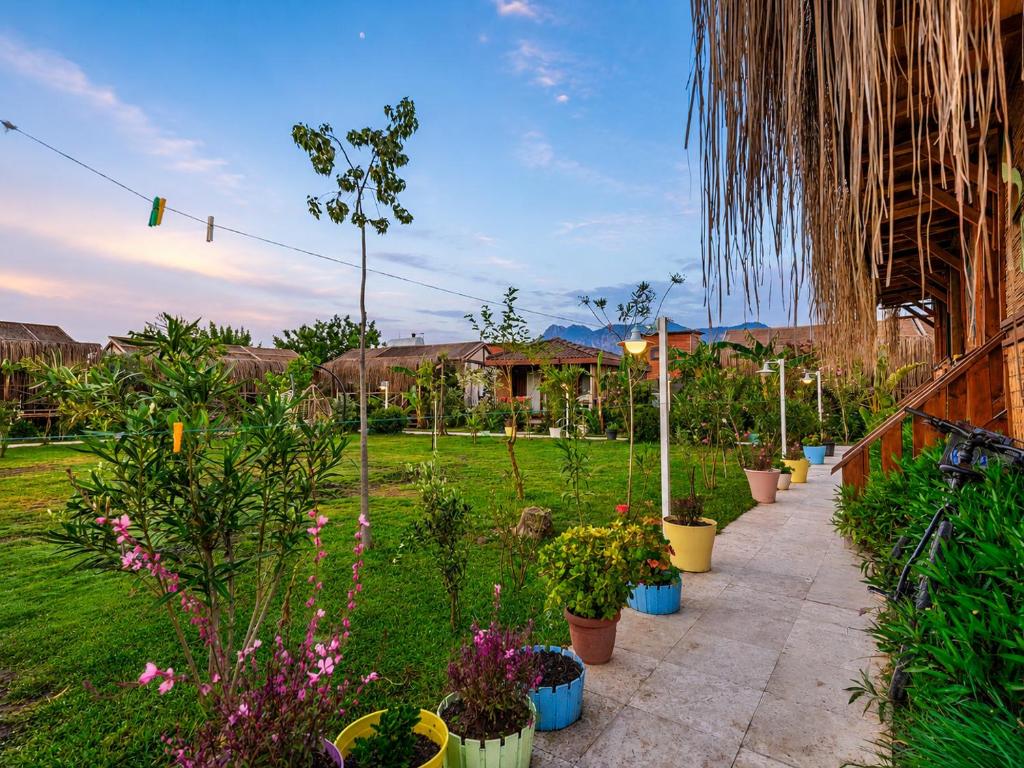 a garden with many potted plants on a sidewalk at Izgen Bungalows in Cıralı