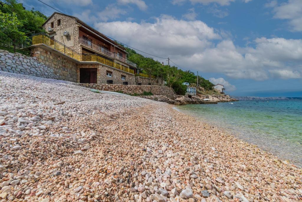 a rocky beach with a building on it next to the water at Apartments Steps from the Sea in Donja Klada
