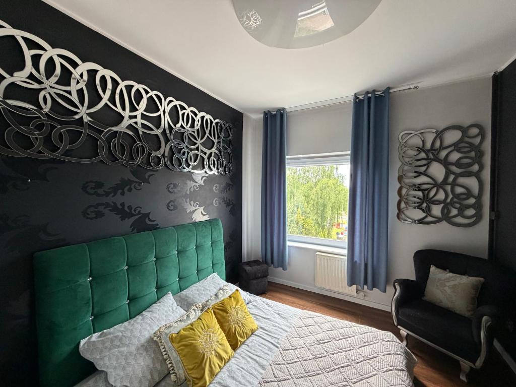 a bedroom with a bed with a green headboard and a window at Glow Rooms in Gdynia