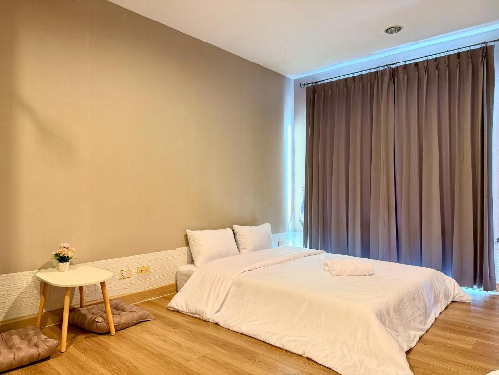 a bedroom with a large bed and a table at The Modern Nest in Ban Bang Chan