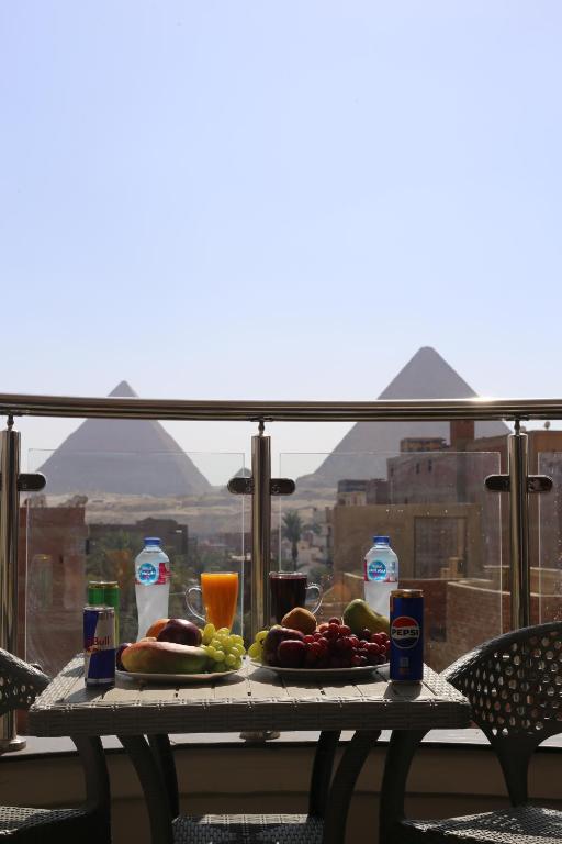 a table with food and drinks on a balcony with a view at Sacred Pyramids Stay in Cairo