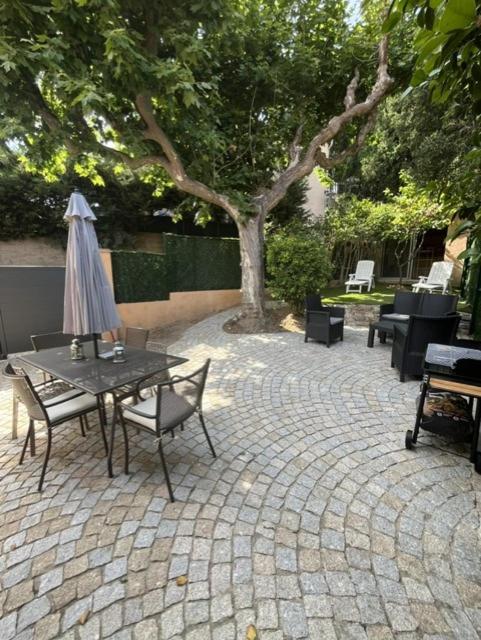 a patio with a table and chairs and an umbrella at Jolie maison de village à Grimaud in Grimaud