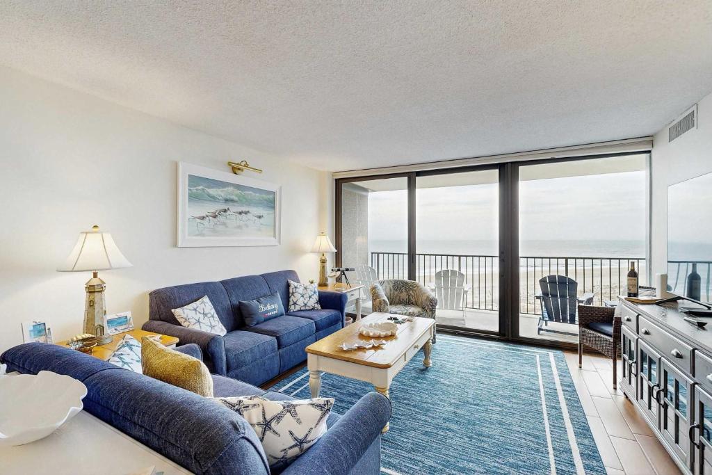a living room with a blue couch and a view of the ocean at Sea Colony - 604 Dover House Rd. in Bethany Beach