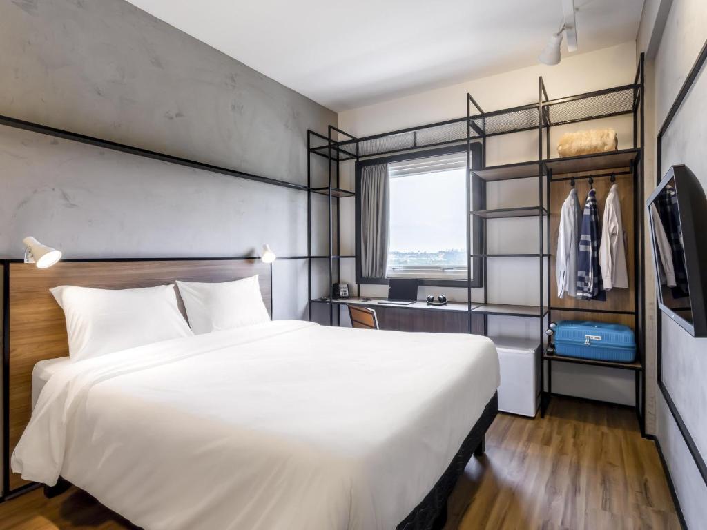 a bedroom with a large white bed and a window at Ibis Aruja in Arujá