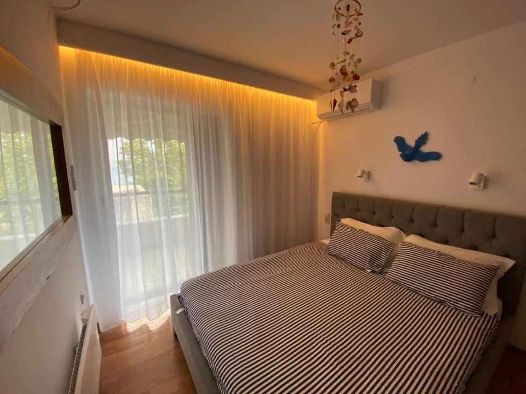 a bed in a bedroom with a large window at Irini Seaside Apartment in Paleo Tsifliki