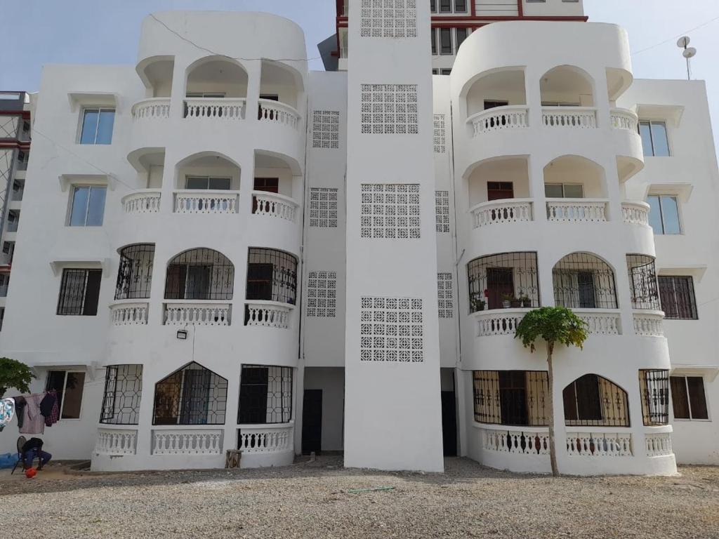 a white building with a tree in front of it at Serene Coastal Suites in Mombasa