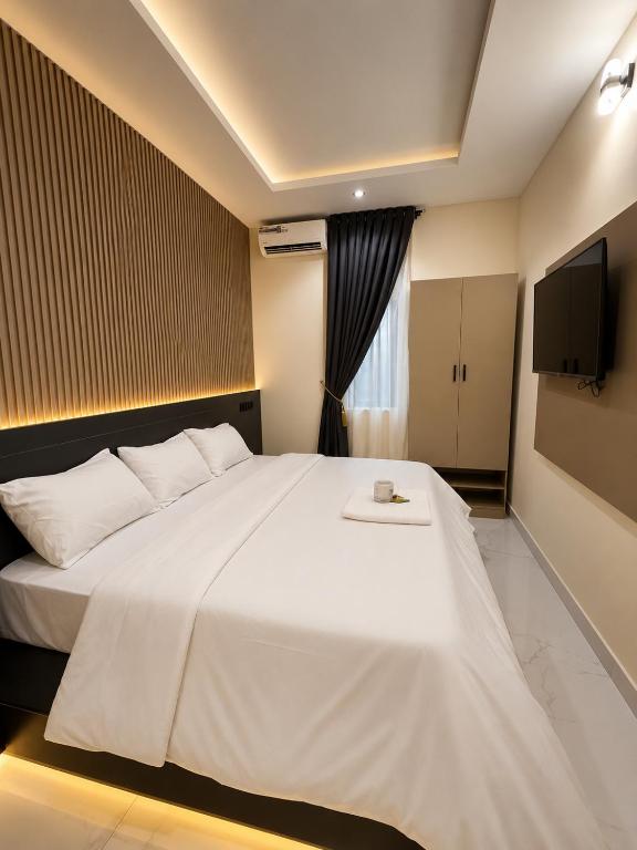 a large white bed in a room with a tv at Leebwill Hotel & Apartment in Eku