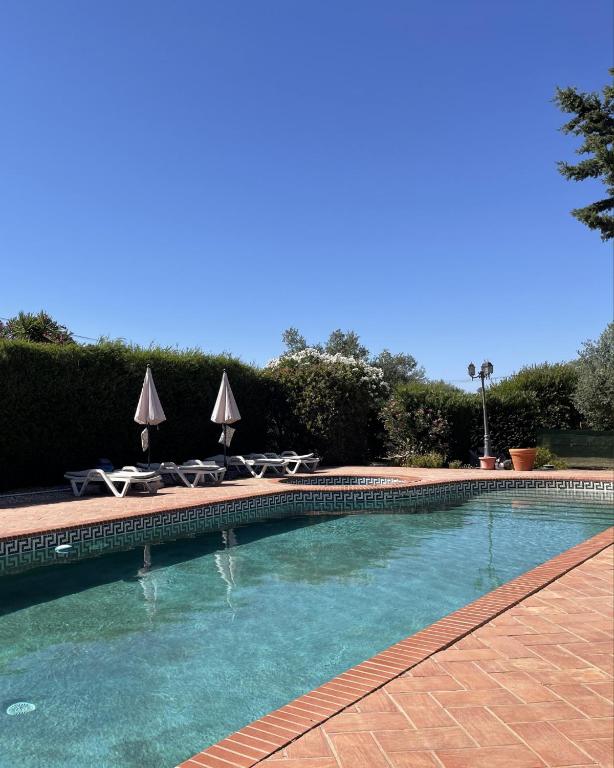 a swimming pool with chairs and umbrellas at Monte da Azinheira in Ourique