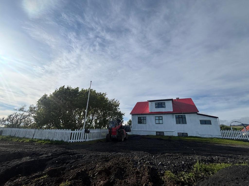 a white house with a red roof next to a fence at Grjótá Historical countryhouse in Hvolsvöllur