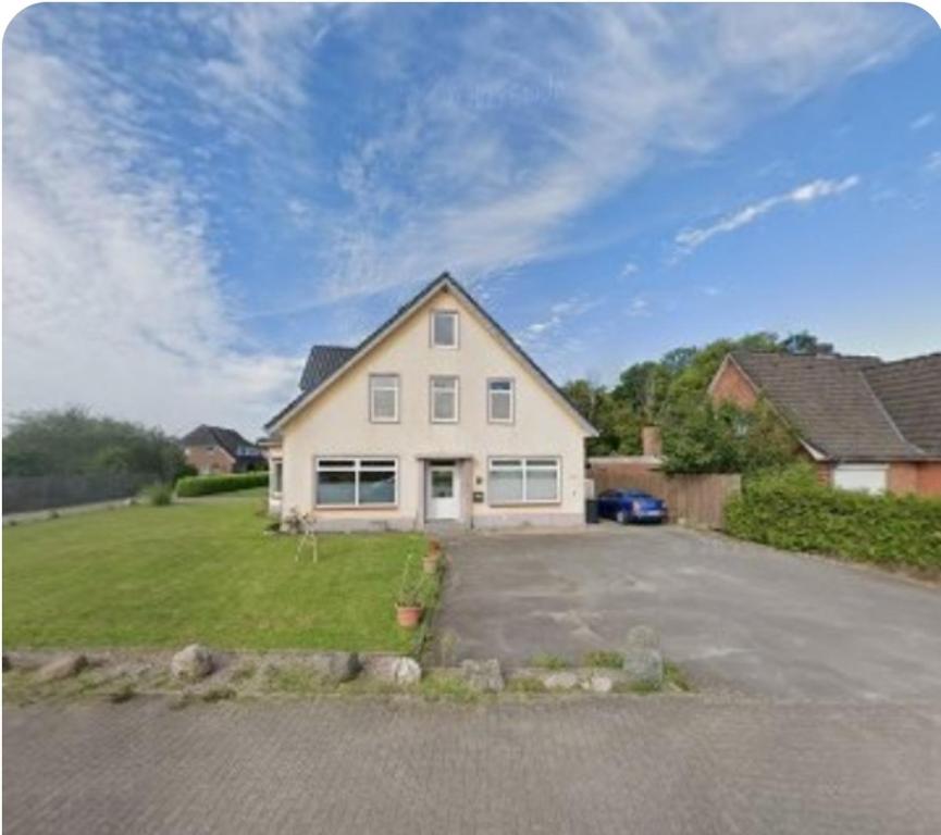 a white house with a parking lot in a yard at Ferienwohnung Küstennah in Großenwiehe