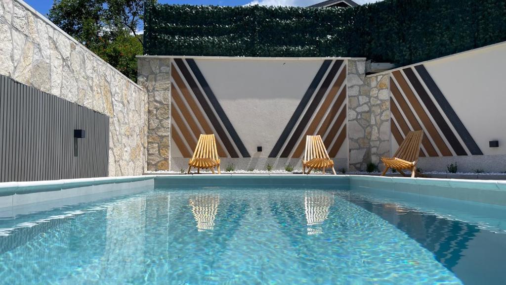 a swimming pool with two chairs in front of a building at MO House Mostar in Kutilivač