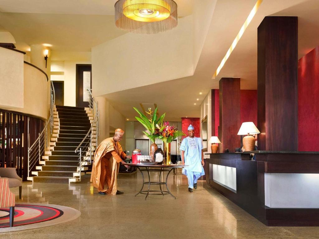 two people walking in a lobby with a table at Mövenpick Hotel Ikoyi Lagos in Lagos
