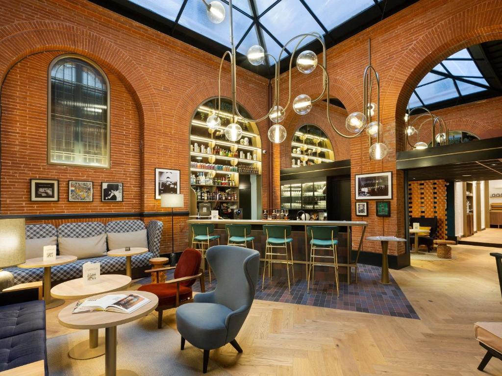 a restaurant with a bar with chairs and tables at Hotel Les Capitouls Toulouse Centre - Handwritten Collection in Toulouse