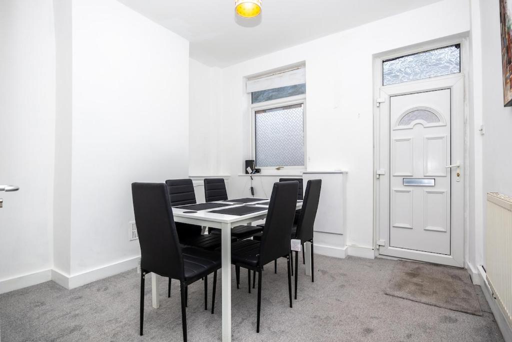 a dining room with a table and black chairs at 2Bd Mid Terrace Close To Station in Stoke on Trent
