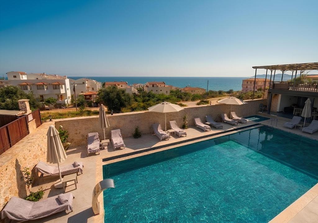 a swimming pool with lounge chairs and the ocean at Beyaz Kosk in Demre