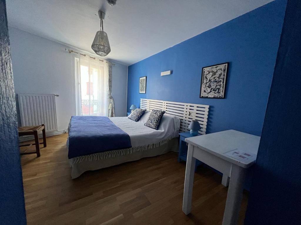 a blue bedroom with a bed and a table at Le Rockastel in Le Caylar
