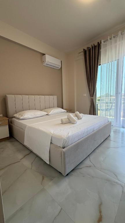 a large white bed in a bedroom with a window at Villa MarJon in Vlorë