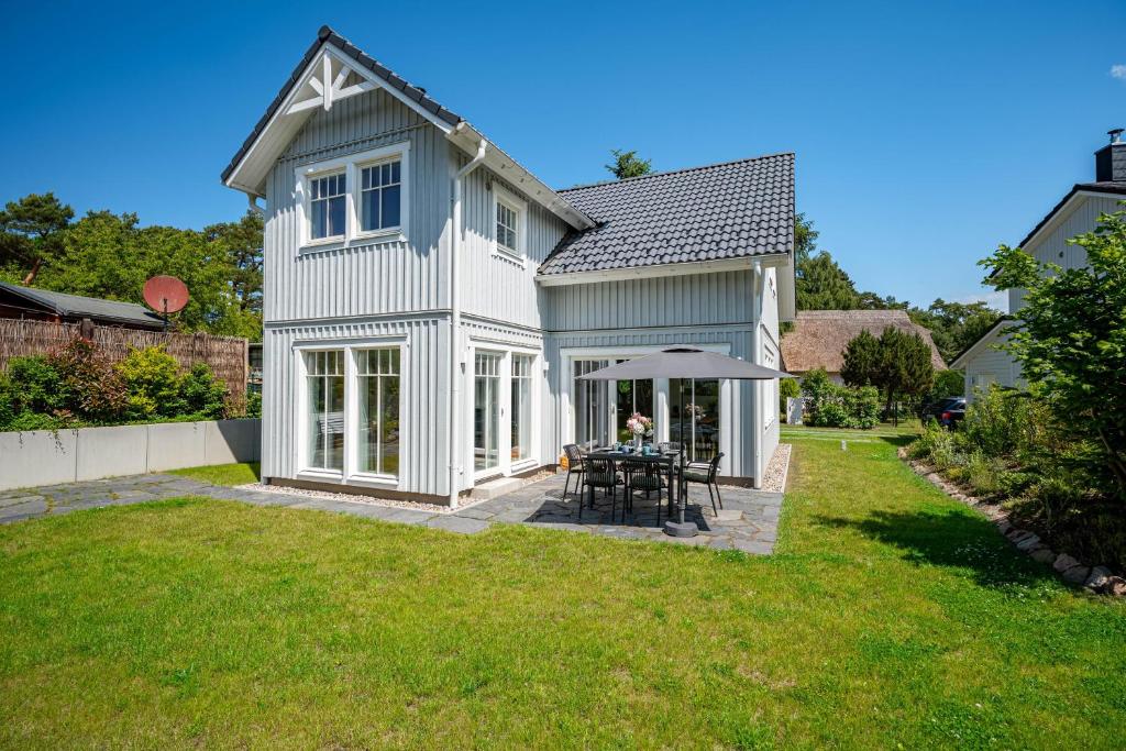a white house with a table and an umbrella at Schwedenhaus Leevsteed in Neuhaus