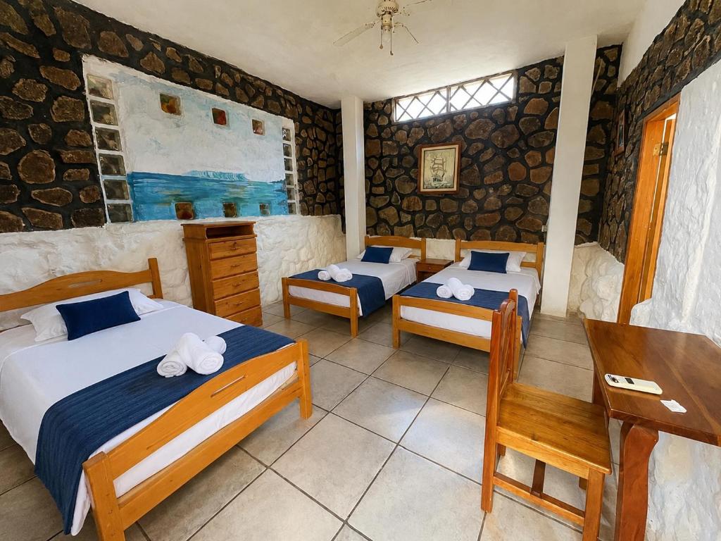 a bedroom with two beds and a table and a desk at Penguin Hostel in Puerto Ayora