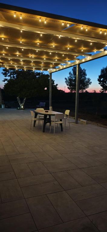 a picnic table and chairs under a pavilion with lights at Villetta della Pace nel cuore del Salento in Torre Santa Susanna