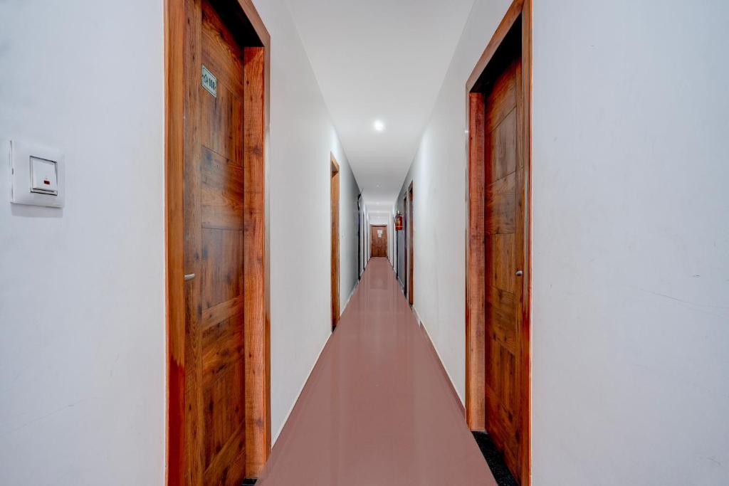 a long corridor with wooden doors and white walls at Super Collection O Bashista Chariali Formerly Luit Heritage in Dispur