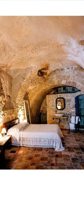 a bedroom with a bed in a stone room at Cave Rooms Sassi in Matera