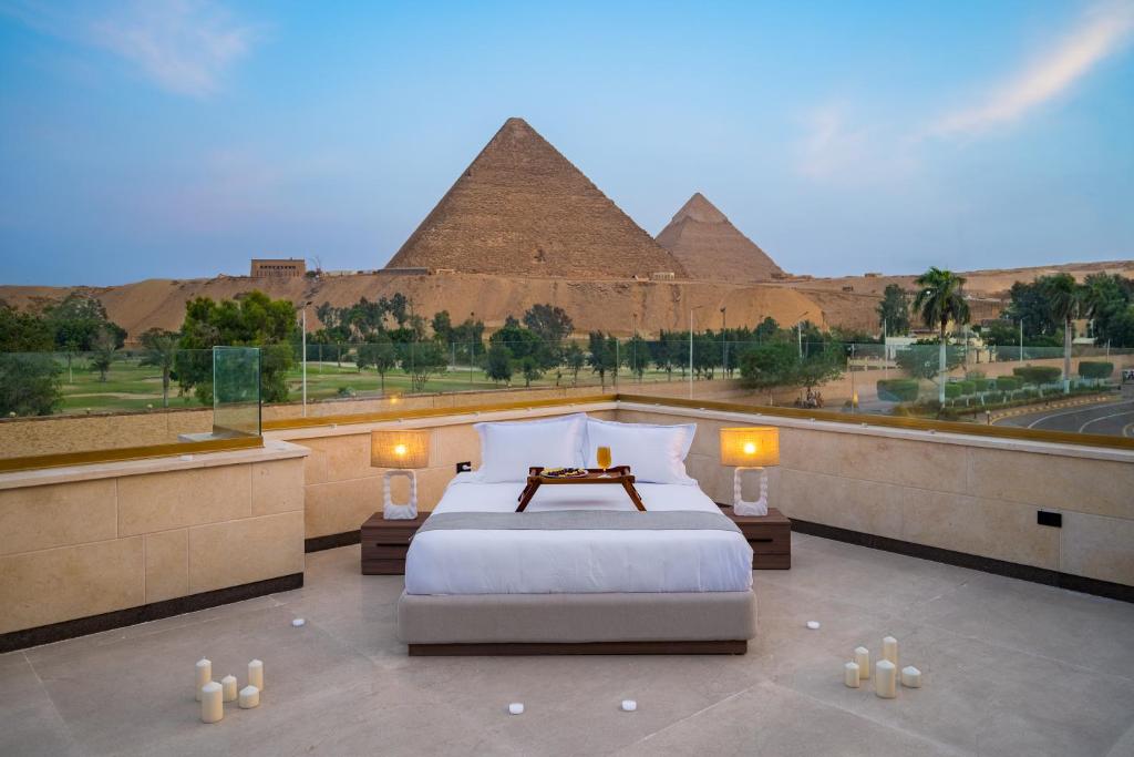a bedroom with a bed with pyramids in the background at Koun Pyramids Hotel in Cairo