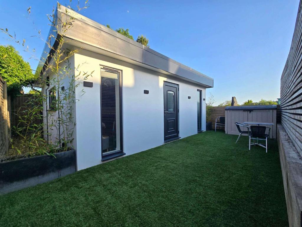 a small white house with a green yard at The Out House in Hemel Hempstead
