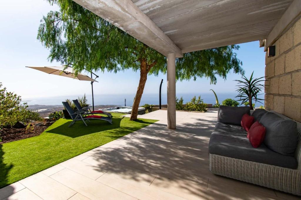 a patio with a couch and chairs on the grass at Infinity House. Ocean View hot tub. in Adeje