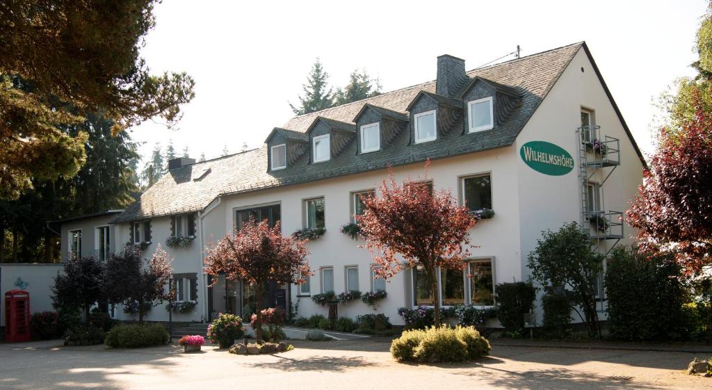 ein weißes Gebäude mit schwarzem Dach in der Unterkunft Hotel Wilhelmshöhe Auderath in Auderath