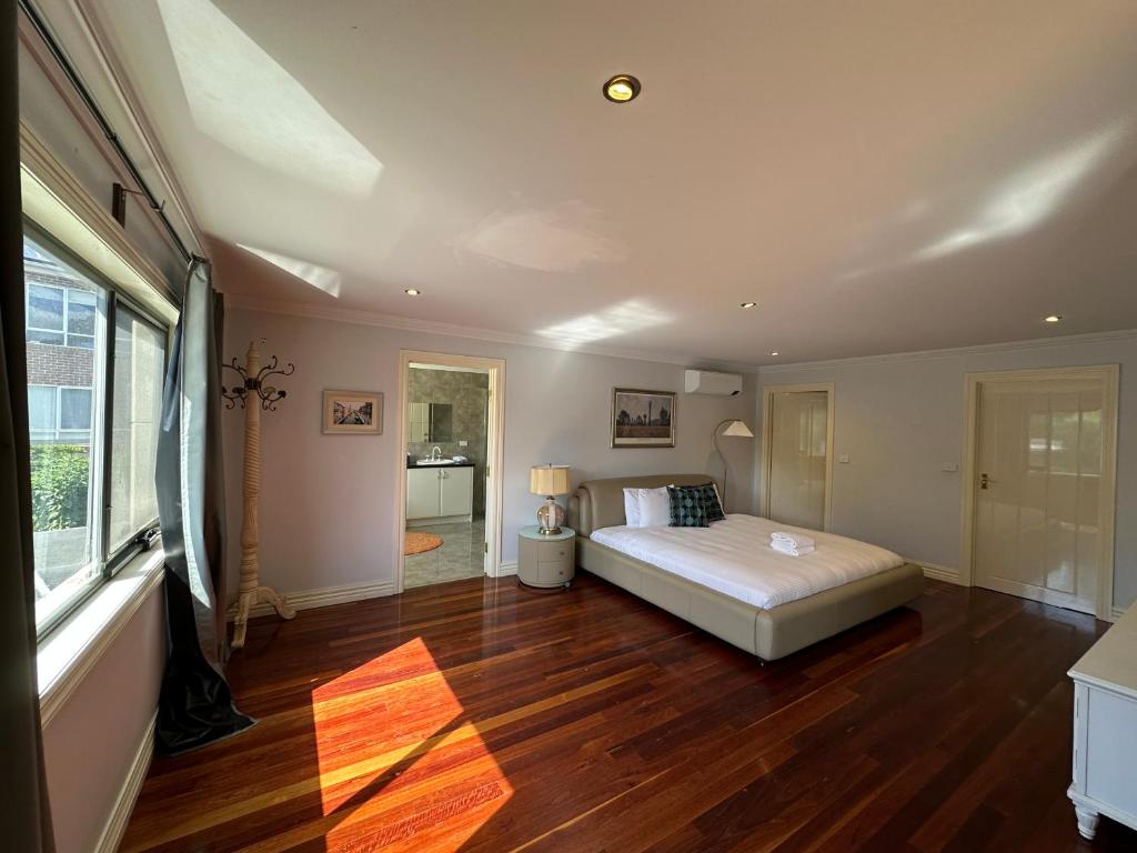 a large bedroom with a bed and wooden floors at Shine House in Balwyn North