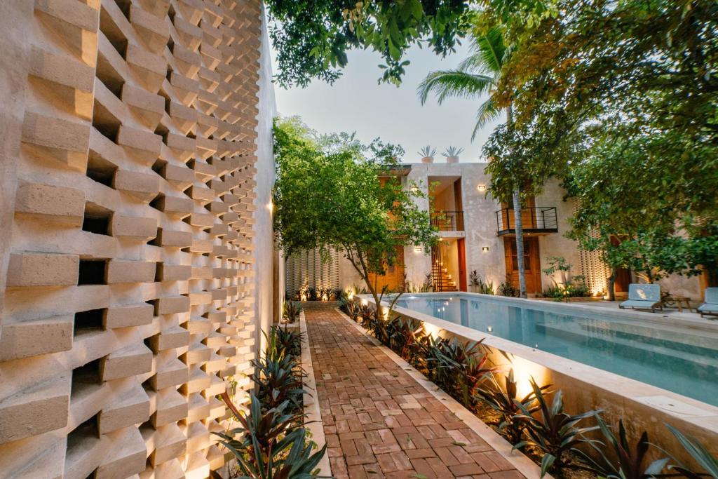 an outdoor swimming pool with a stone wall next to a house at Hotel Boutique Alma Peregrina in Valladolid
