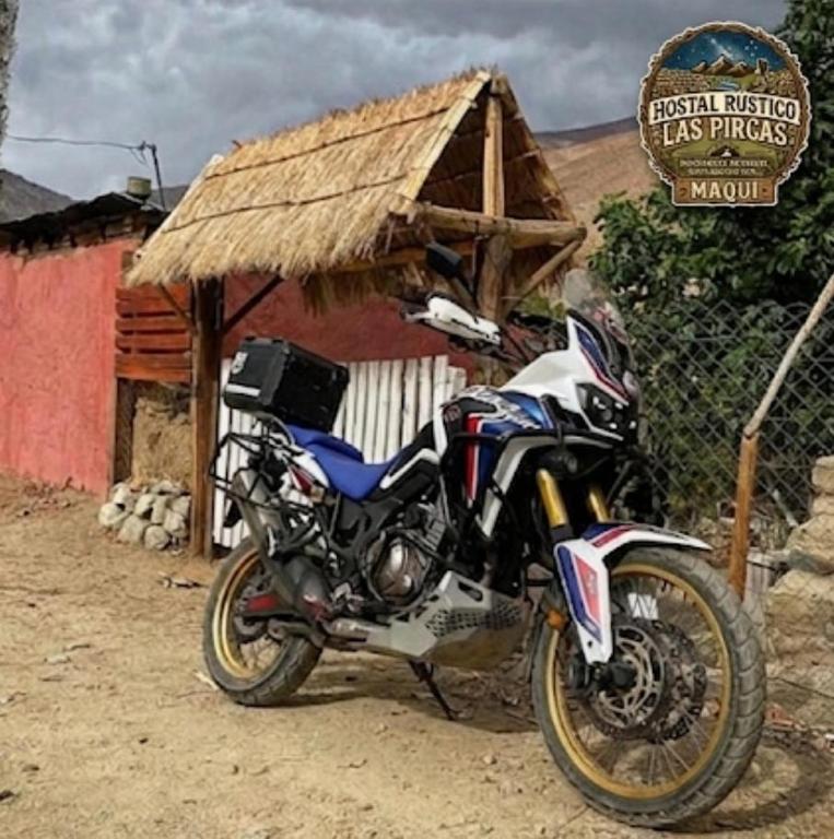 a motorcycle parked in front of a small hut at Hostal Rústico Las Pircas in Alcoguaz