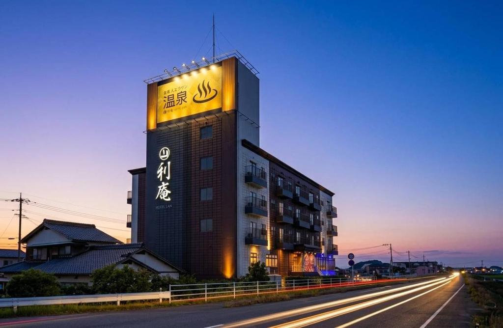 a building with a sign on it next to a road at HOTEL Lien in Ashiya